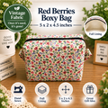 A floral boxy bag made from vintage-style fabric, displayed on a wooden surface with decorative props. The bag features a red, pink, and green floral pattern on a cream background.