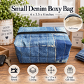 A small denim boxy bag made from blue denim fabric with a black zipper, shown on a wooden tabletop with decorative plants and boxes in the background. Text at the top reads 'Small Denim Boxy Bag' with dimensions '6 x 3.