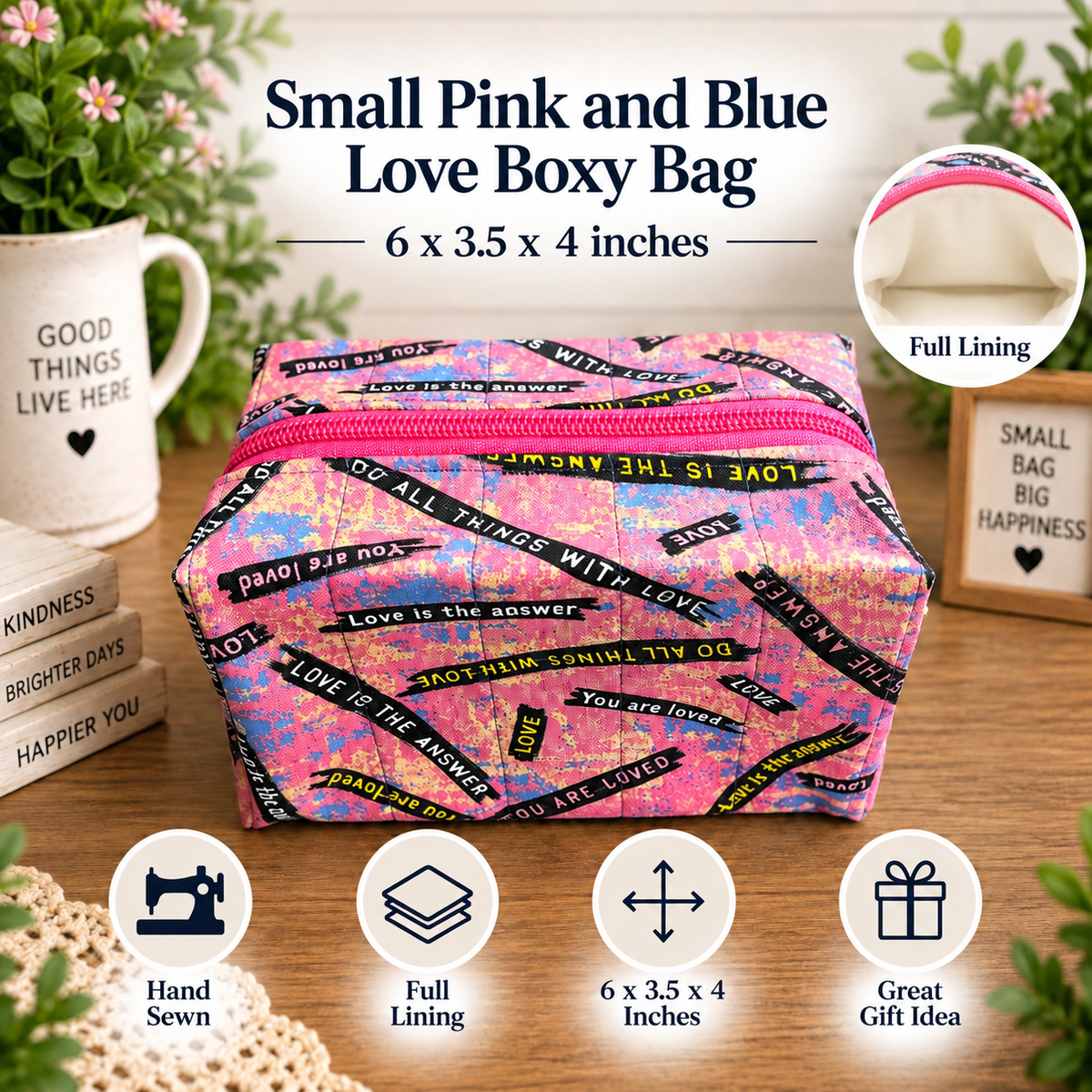 A pink and blue patterned fabric boxy bag with a pink zipper, displayed on a wooden surface with decorative props including a mug, flowers, and small boxes. Text at the top reads 'Small Pink and Blue Love Boxy Bag' with dimensions, and circular icons at the bottom highlight features like hand sewing, full lining, size, and gift suitability.