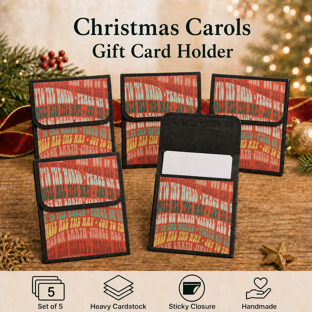 Five Christmas carols gift card holders arranged on a wooden surface with holiday decorations in the background. The holders feature a red, green, and gold patterned cover with black edges and a black interior pocket.