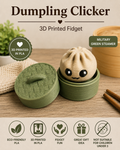 A 3D printed dumpling-shaped fidget toy with a cute face sitting in a round green steamer container, shown alongside its matching lid on a tabletop. The image includes marketing text reading 'Dumpling Clicker' and '3D Printed Fidget,' plus icons for eco-friendly PLA, 3D printed PLA, fidget fun, great gift idea, and not suitable for children under 3.