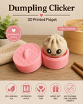 A pink 3D printed dumpling-shaped fidget toy labeled 'Dumpling Clicker' shown open on a wooden surface, with a pink lid beside it. The dumpling has a cute face, and the scene includes decorative props and text callouts including 'Pink Steamer' and feature icons along the bottom.