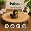 A small articulated falcon figurine displayed on a round wood slice coaster. The product is black with a brown body and a yellow beak, with text reading 'Falcon Articulated Flexi Figure' and feature icons below.