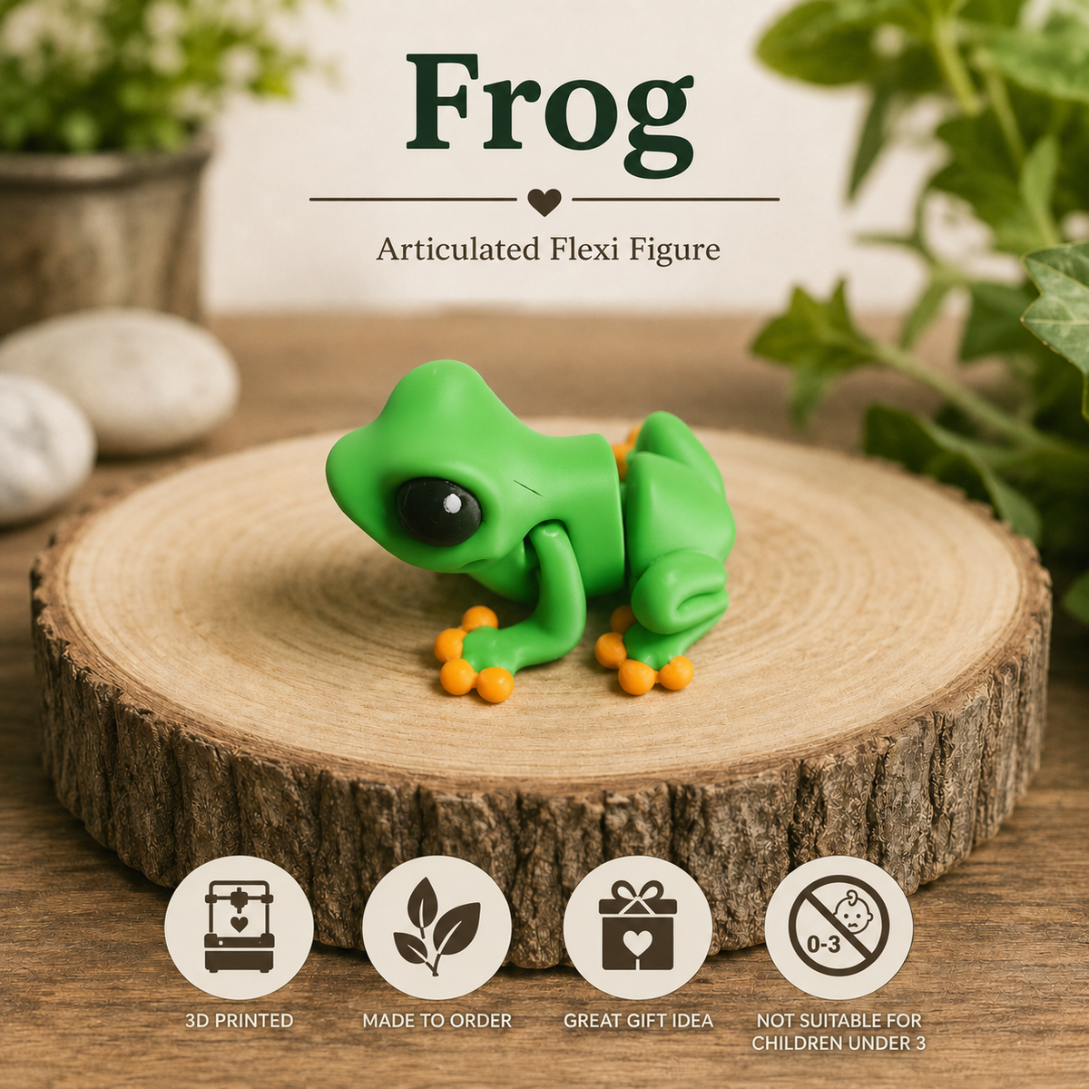 A green frog articulated flexi figure with orange feet sits on a round wood slice. The background is a styled tabletop scene with blurred green plants and stones, and text at the top reads 'Frog' and 'Articulated Flexi Figure.