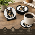 Four round German shepherd dog portrait coasters with black holders and cork bottoms are arranged on a wooden table, alongside a mug of coffee and a plant. Text at the bottom highlights the set features.