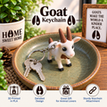 A small goat keychain with a white and brown goat figure attached to a silver key ring, displayed on a ceramic dish with keys. The scene includes decorative plants, a framed sign, and text overlays reading 'Goat Keychain' plus feature icons at the bottom.