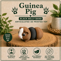 A 3D-printed articulated Guinea Pig toy with a brown and white head, black belly, and brown tail, displayed on a wood slice coaster. The background is a textured beige graphic with text overlays reading 'Guinea Pig BLACK BELLY BAND ARTICULATED 3D PRINTED TOY' and feature icons at the bottom.