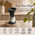 Black and white hour glass fidget spinner displayed on a marble coaster on a kitchen counter, with text overlays and feature icons at the bottom.