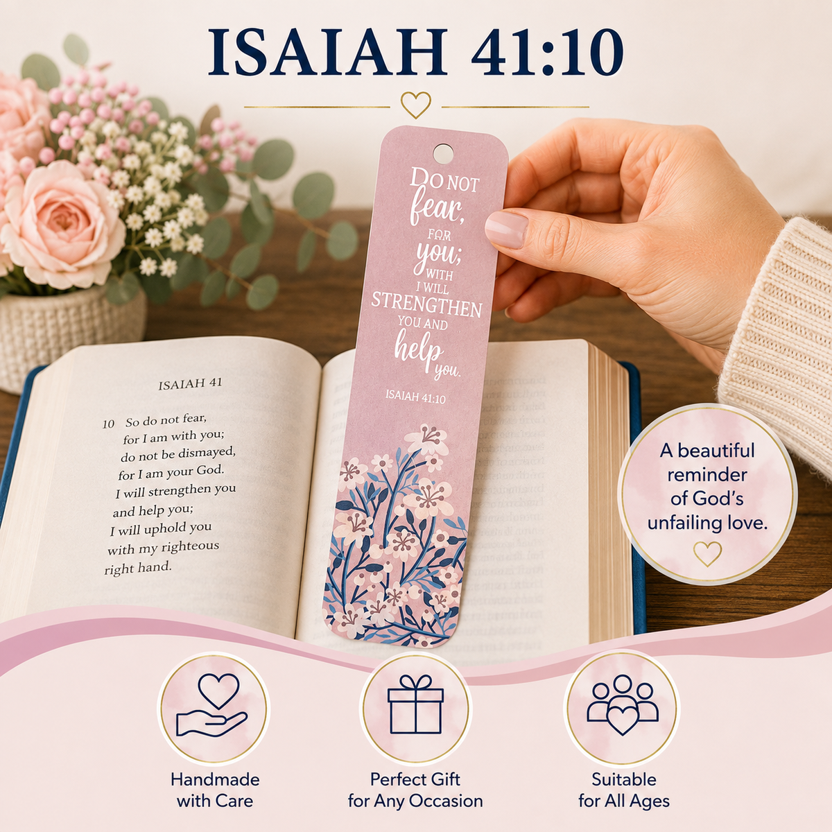 A pink floral bookmark featuring the Bible verse Isaiah 41:10 is held by a hand over an open book. The image includes decorative pink flowers, a white sweater sleeve, and promotional text highlighting the bookmark's message and gift appeal.