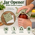 A jar opener with green leaves patterned fabric, being used by hands to lift the lid of a glass jar. The image includes text overlays and circular inset graphics showing the product details and features.