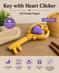 A yellow 3D-printed key-shaped fidget toy with a purple heart in the center, shown on a wooden surface with decorative props. The image includes text reading 'Key with Heart Clicker,' '3D Printed Fidget,' and 'Purple Heart,' plus feature icons along the bottom.