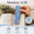 A hand holds a blue floral bookmark with Bible verse text from Matthew 11:28 over an open book. The scene includes decorative flowers, a large title reading 'Matthew 11:28,' and circular callout badges with product benefits like 'Handmade with Care,' 'Perfect Gift for Any Occasion,' and 'Suitable for All Ages.