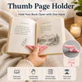 A pink thumb page holder shown being used to hold an open book with one hand, with promotional text and a circular inset showing the product color. The scene includes a cozy blanket background and a softly blurred indoor setting.