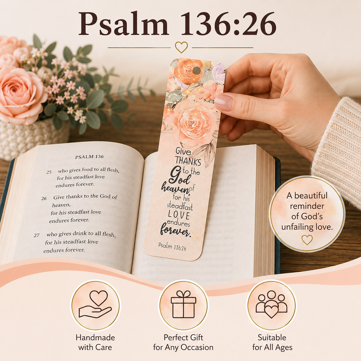 A hand holds a floral bookmark with Psalm 136:26 text over an open book. The bookmark has peach and pink watercolor flowers, green leaves, and black lettering.