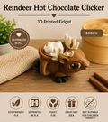 A 3D printed brown reindeer-shaped hot chocolate fidget toy with white antlers and marshmallows inside its head, displayed on a wooden table with promotional text overlays.