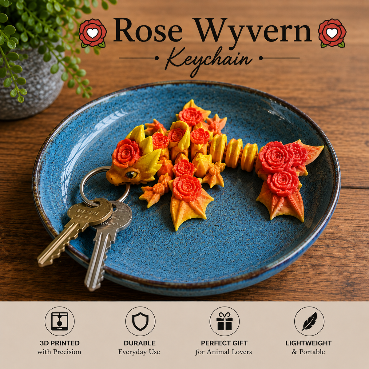 A decorative keychain shaped like a rose wyvern, shown resting on a blue ceramic plate with two keys. The keychain features yellow and orange rose-shaped scales and wings.