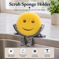 A yellow smiley-face sponge held in a gray plastic holder with legs, shown on a kitchen sink counter with text reading 'Scrub Sponge Holder' and feature icons along the bottom.