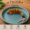 Orange and black stripped tiger keyring in a bowl that is sitting on a table