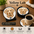 Set of four round coasters designed for a yellow lab dog, featuring a printed illustration of a yellow lab's face and a small black paw print. The coasters have cork bottoms and are displayed on a wooden table alongside a coffee cup, with text highlighting eco-friendly PLA plastic and product features.